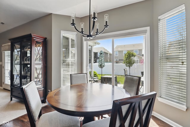 dining area with baseboards, an inviting chandelier, and wood finished floors