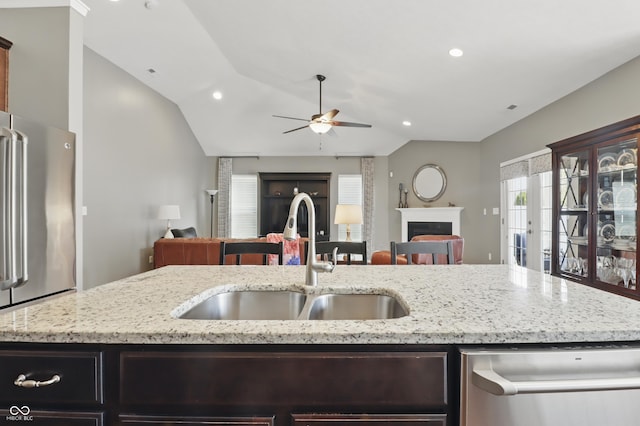 kitchen featuring a fireplace, vaulted ceiling, a sink, open floor plan, and stainless steel appliances