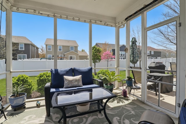 sunroom featuring a residential view and track lighting
