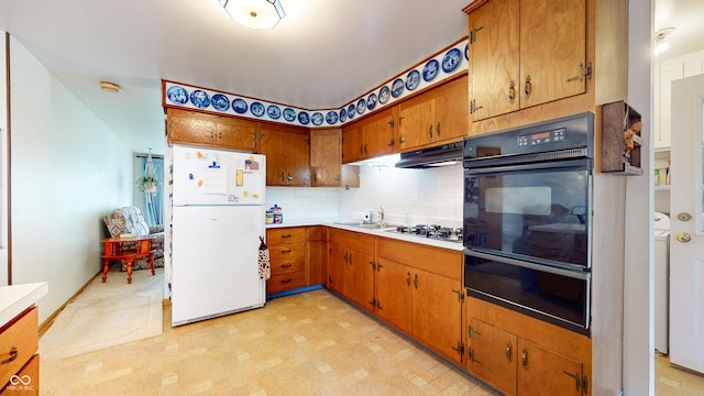 kitchen featuring light countertops, black oven, freestanding refrigerator, under cabinet range hood, and a warming drawer