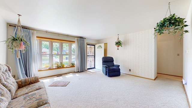 carpeted living room featuring baseboards, visible vents, and wallpapered walls