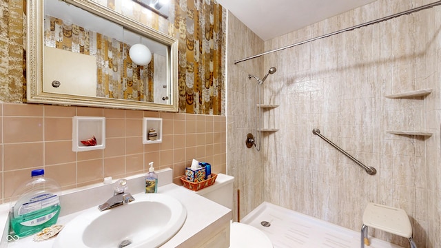 bathroom with vanity, tile walls, toilet, and tiled shower