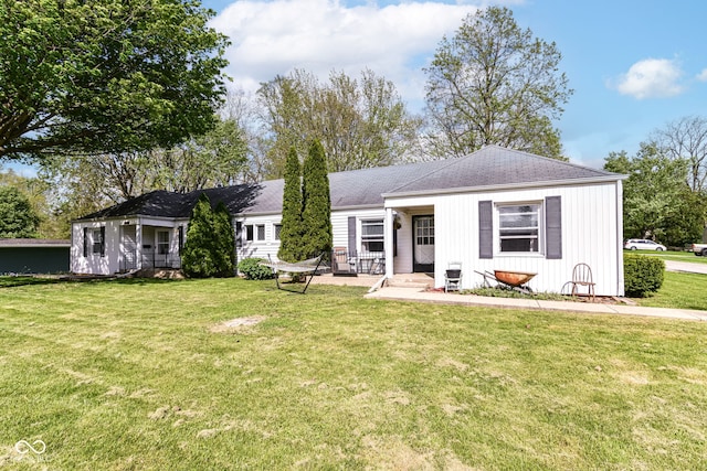 ranch-style house featuring board and batten siding, covered porch, a shingled roof, and a front yard