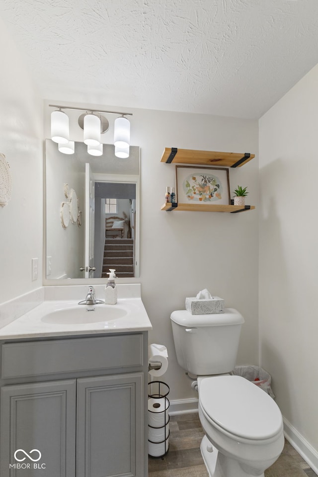 5845 Cresswell Ln, Whitestown, IN 46075 - half bath featuring toilet, vanity, a textured ceiling, baseboards, and wood finished floors