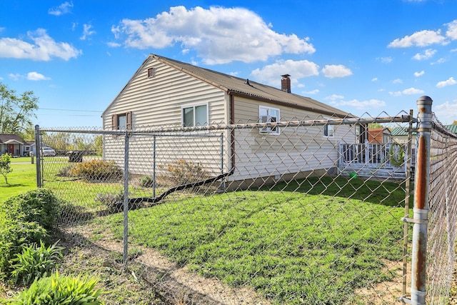 view of side of home featuring fence, a chimney, and a yard
