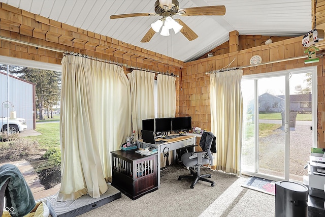 carpeted home office with a ceiling fan, lofted ceiling, and wooden walls