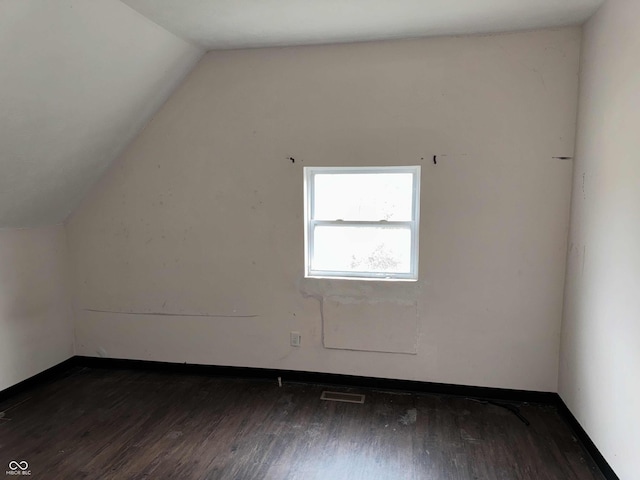 additional living space with vaulted ceiling, dark wood finished floors, and visible vents