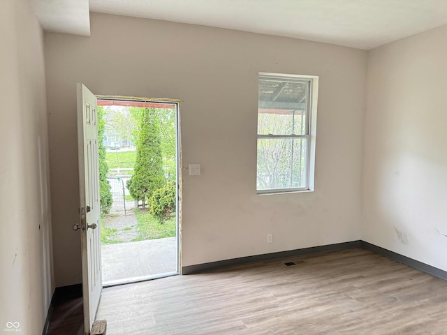 interior space with baseboards, wood finished floors, and visible vents