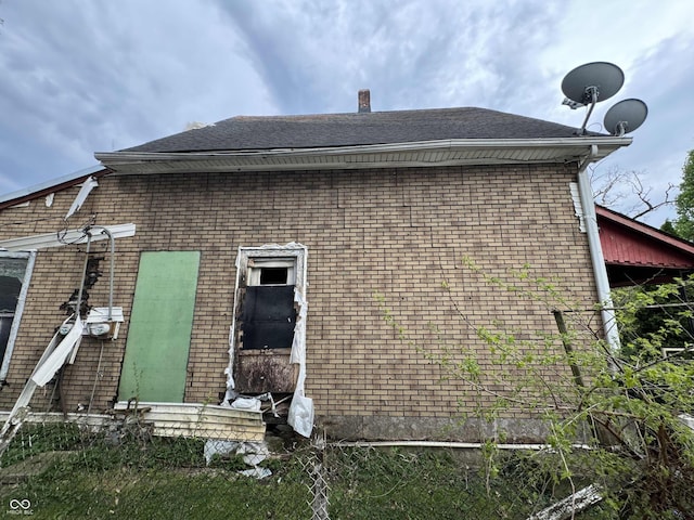 rear view of house featuring brick siding, a shingled roof, and entry steps