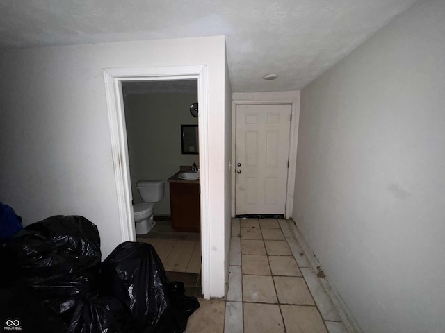 hallway featuring a sink and light tile patterned flooring