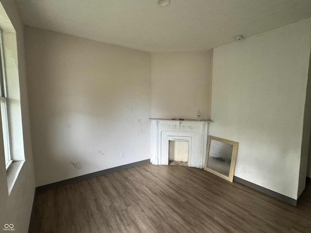 unfurnished living room featuring baseboards, wood finished floors, and a fireplace