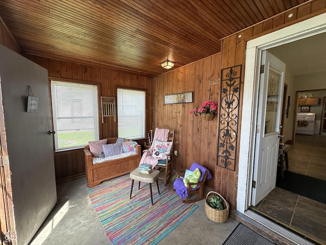 sitting room with wooden walls, wood ceiling, and concrete flooring
