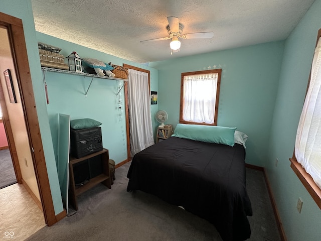 carpeted bedroom featuring baseboards, a textured ceiling, and ceiling fan