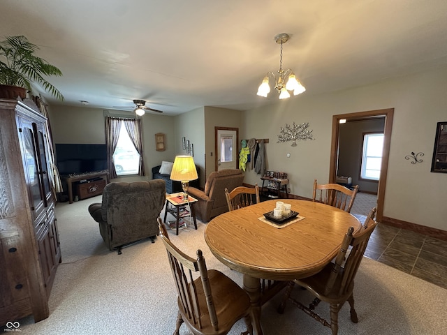 carpeted dining area with baseboards and ceiling fan with notable chandelier