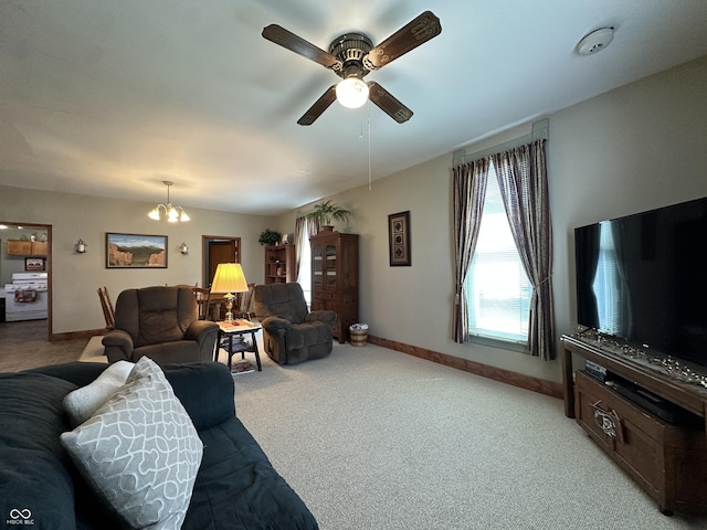 living room featuring baseboards, light carpet, and ceiling fan with notable chandelier