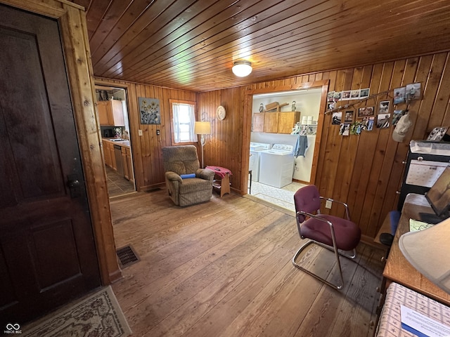 sitting room with wood walls, wooden ceiling, washer and clothes dryer, and hardwood / wood-style flooring