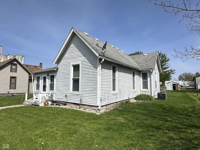 view of home's exterior featuring a lawn, central AC unit, and roof with shingles