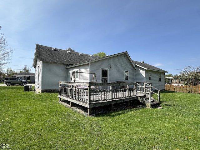 rear view of house with a wooden deck, central air condition unit, fence, a yard, and a shingled roof