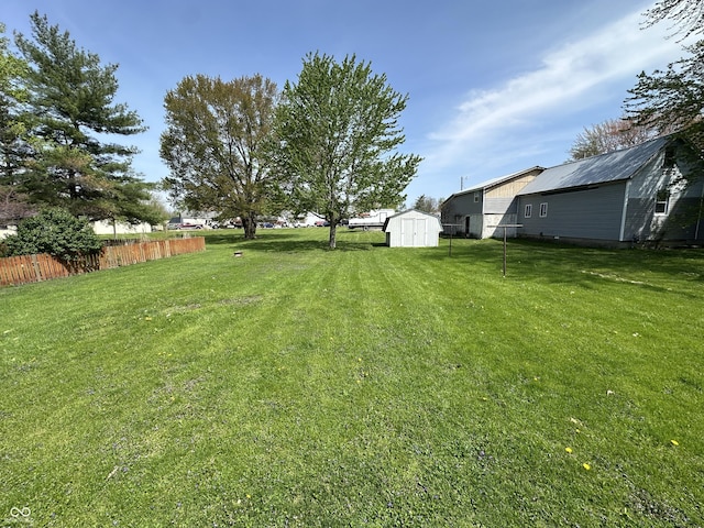 view of yard featuring a storage shed, fence, and an outbuilding