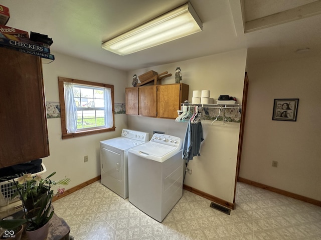 washroom featuring visible vents, cabinet space, baseboards, light floors, and washer and clothes dryer