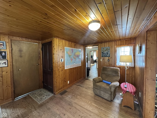living area featuring wood-type flooring, wood walls, visible vents, and wooden ceiling