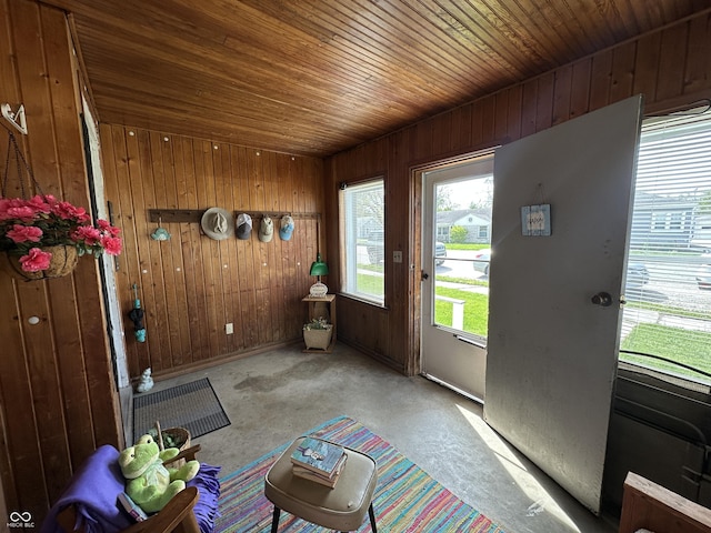 doorway with wooden walls, unfinished concrete floors, and wooden ceiling