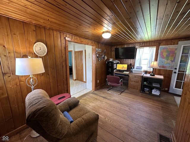 office space featuring light wood-style floors, wood walls, visible vents, and wooden ceiling