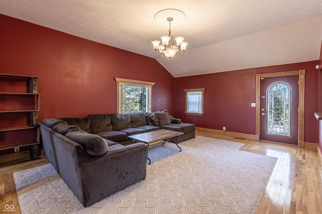 living area with light wood-type flooring, baseboards, a chandelier, and vaulted ceiling