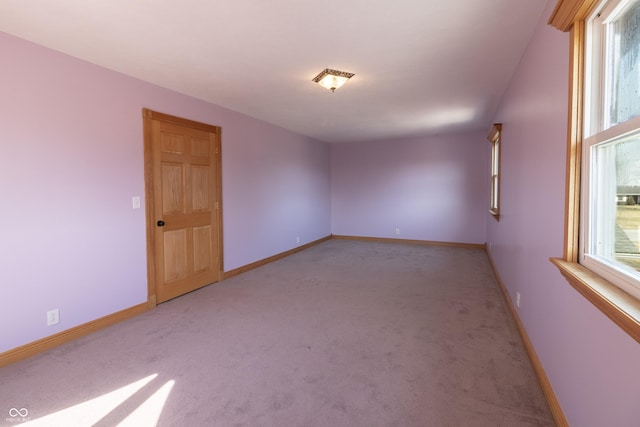 unfurnished room with baseboards and light carpet