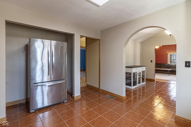 kitchen with freestanding refrigerator, arched walkways, and baseboards