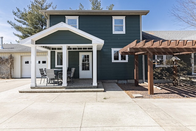 rear view of property with an attached garage and a pergola