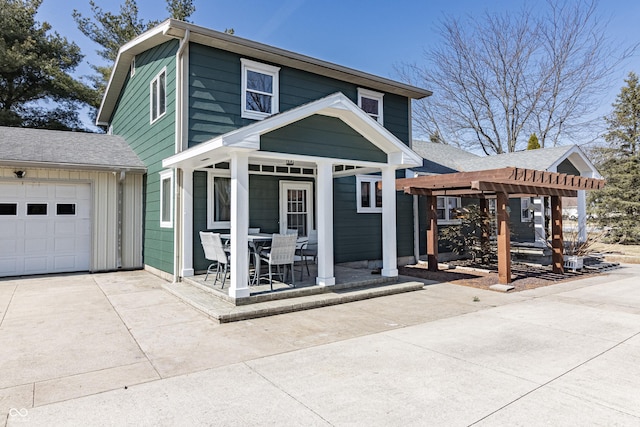 traditional-style home featuring driveway, a patio area, a pergola, an attached garage, and outdoor dining space