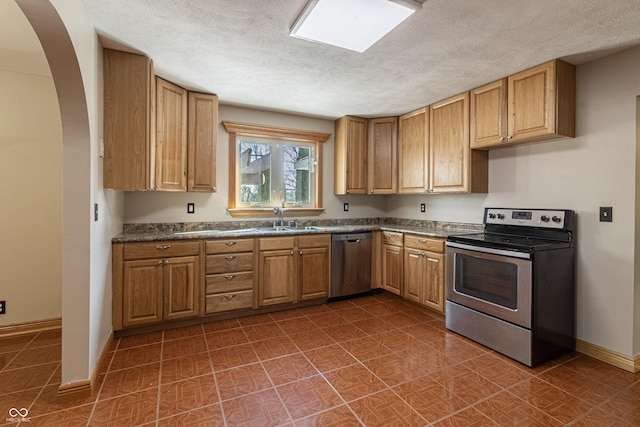 kitchen with stainless steel appliances, dark countertops, baseboards, and a textured ceiling