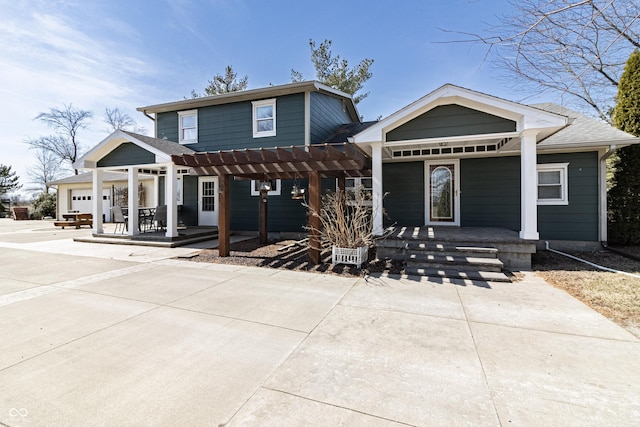 back of house with covered porch, an attached garage, and concrete driveway