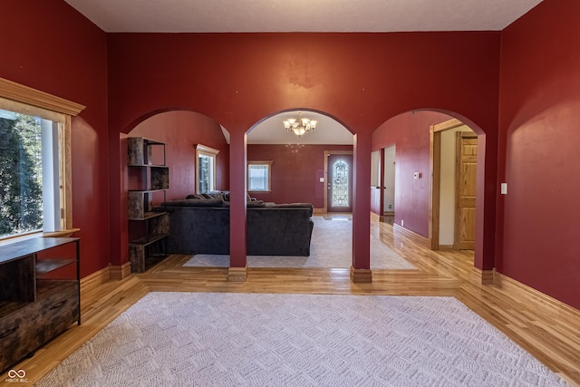 unfurnished living room with arched walkways, plenty of natural light, and wood finished floors