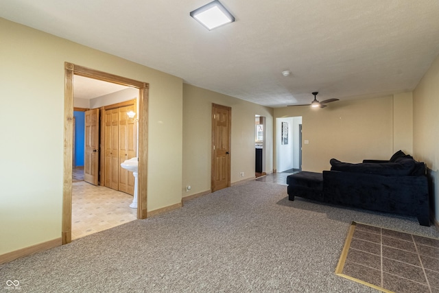 carpeted living area featuring ceiling fan and baseboards