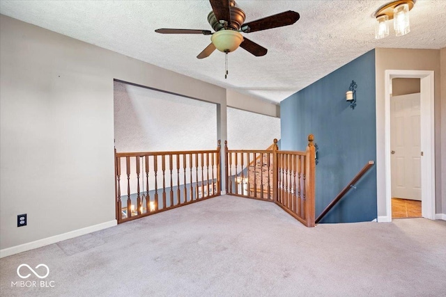 carpeted empty room with baseboards, a ceiling fan, and a textured ceiling