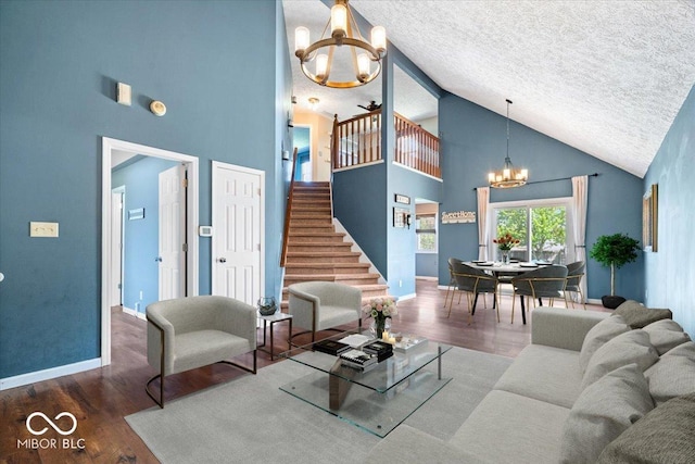 living area with a textured ceiling, wood finished floors, high vaulted ceiling, an inviting chandelier, and stairs