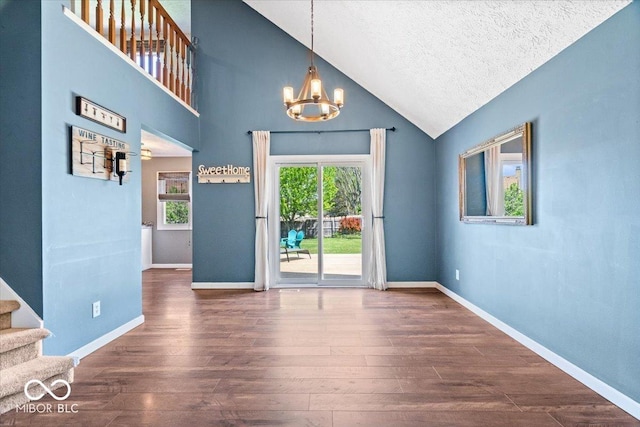 doorway to outside with wood finished floors, stairway, high vaulted ceiling, baseboards, and a chandelier