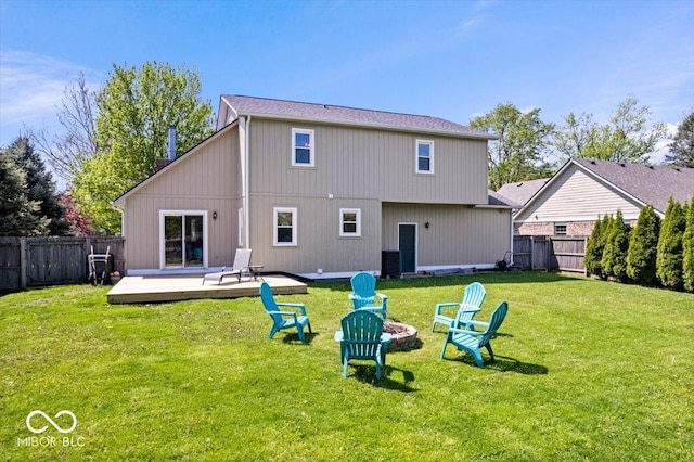 rear view of property with a fire pit, a wooden deck, central AC, a fenced backyard, and a lawn