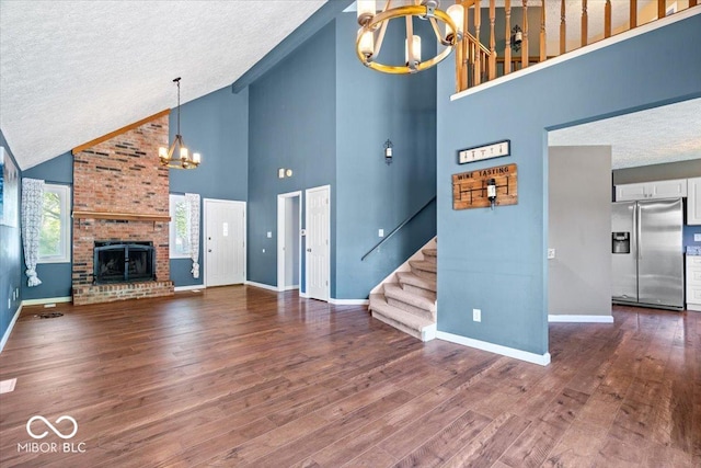 unfurnished living room with stairs, a textured ceiling, high vaulted ceiling, and a notable chandelier