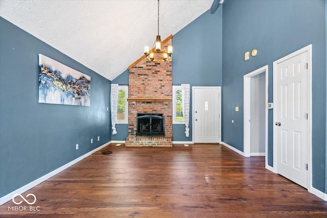 unfurnished living room with wood finished floors, a fireplace, high vaulted ceiling, a textured ceiling, and a notable chandelier