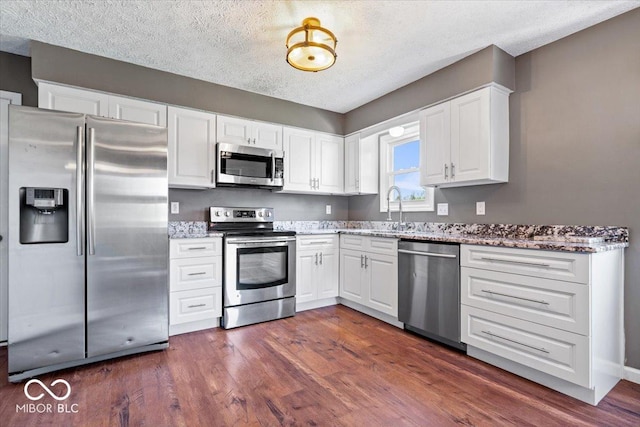kitchen featuring a sink, appliances with stainless steel finishes, a textured ceiling, and white cabinetry