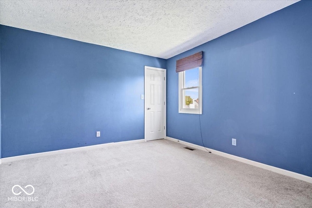 carpeted empty room featuring baseboards and a textured ceiling