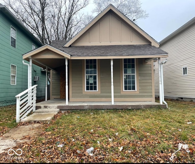 view of front of home with a porch, board and batten siding, a shingled roof, and a front lawn
