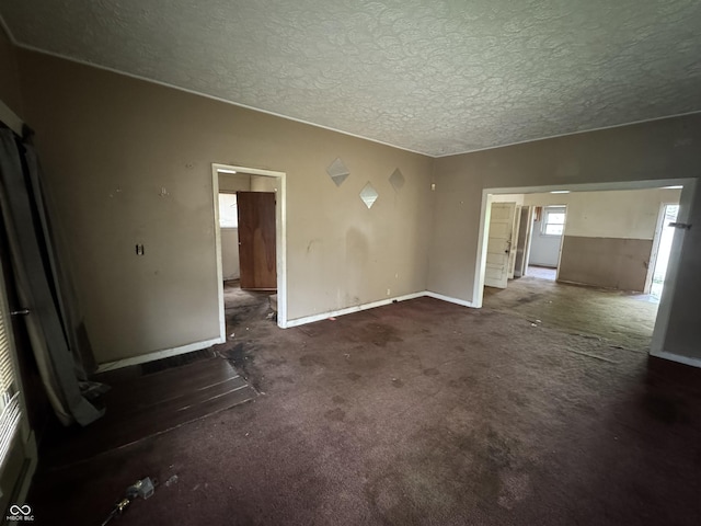 empty room featuring baseboards, carpet flooring, and a textured ceiling