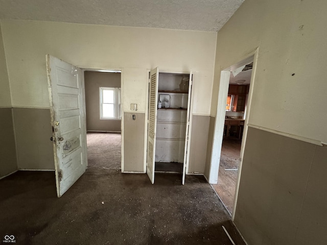 unfurnished bedroom featuring a textured ceiling and wainscoting