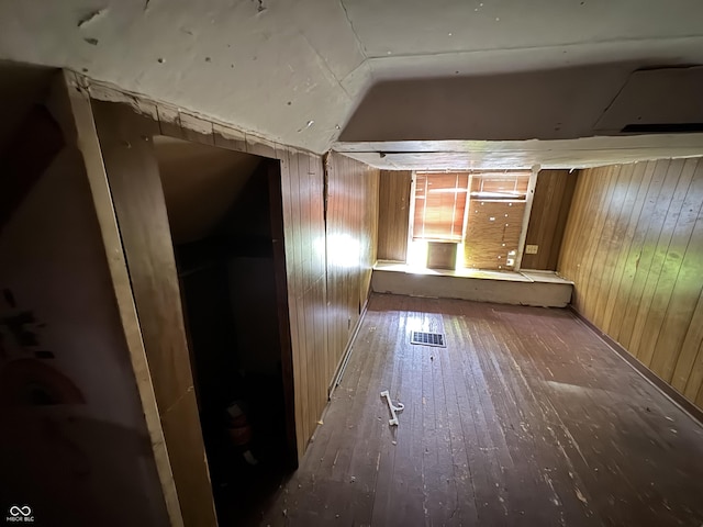 hall featuring wood walls, lofted ceiling, and hardwood / wood-style floors