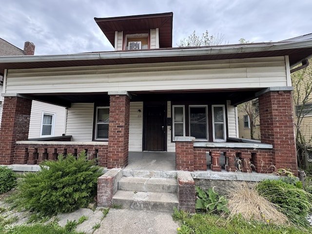 view of front of house with a porch and brick siding
