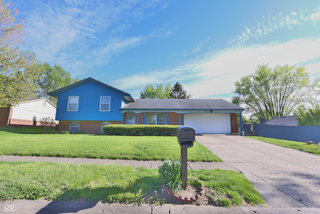 split level home featuring brick siding, an attached garage, driveway, and a front lawn